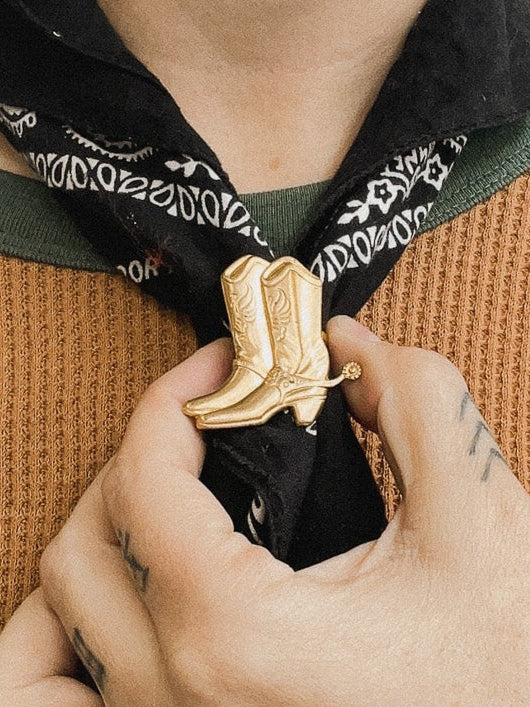 Person wearing a green and brown shirt with a black bandana around their neck.