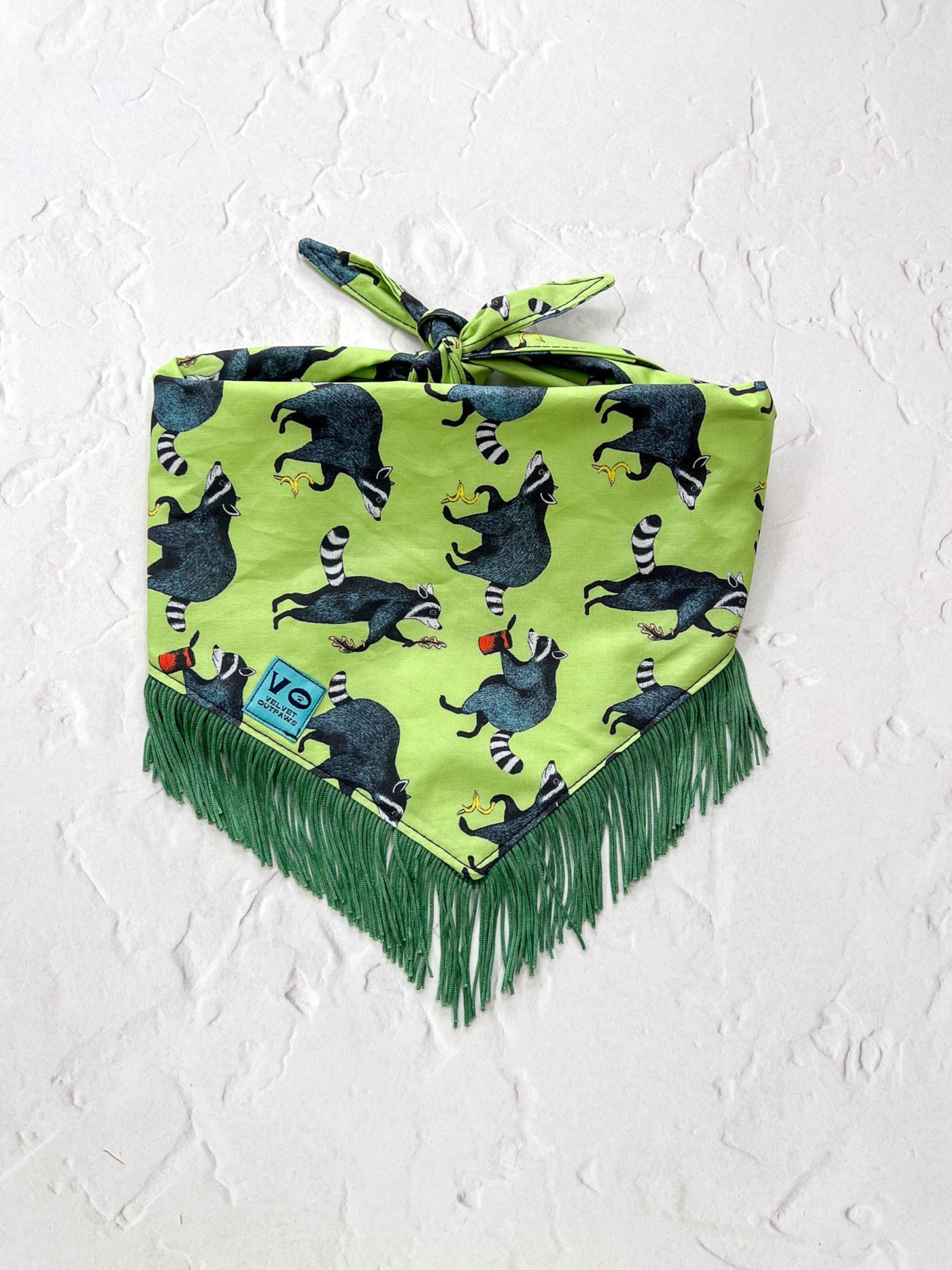 Green bandana with raccoon pattern and fringes on a white background